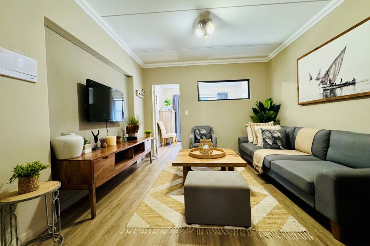 A well-maintained living room featuring laminate flooring, cove cornicing, and a recessed wall niche, creating a comfortable and inviting space.