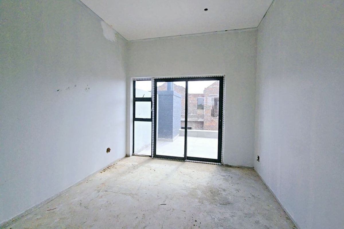 An unfinished bedroom space featuring a sliding glass door leading to an outdoor area, requiring flooring and final wall finishes.
