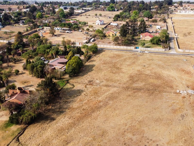 An aerial view of a large, vacant residential plot of land in a semi-rural setting, showing surrounding properties and access roads.