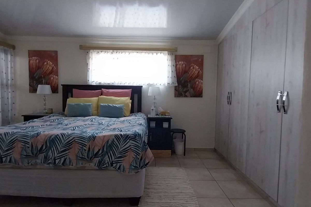 A well-lit bedroom featuring built-in floor-to-ceiling wardrobes, tiled flooring, and large windows allowing for natural light.
