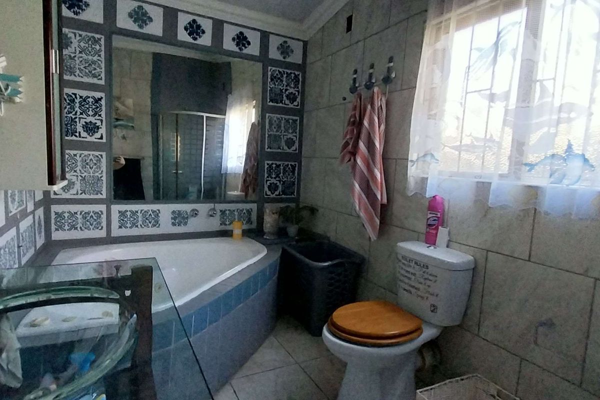 A functional bathroom featuring a corner bathtub, a glass vessel sink, and tiled walls with decorative accents.