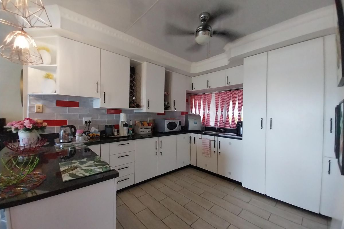 A well-maintained kitchen featuring white cabinetry, dark granite countertops, a tiled backsplash, and a ceiling fan.