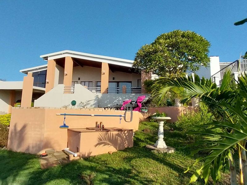 A view of the rear exterior of the house, featuring a raised patio area, landscaped garden, and integrated structural elements.