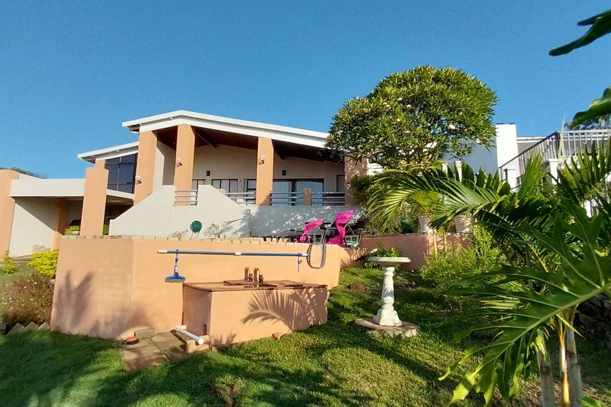 A view of the rear exterior of the house, featuring a raised patio area, landscaped garden, and integrated structural elements.