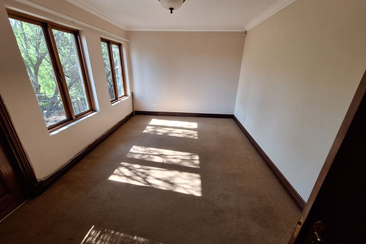 An empty bedroom featuring carpet flooring, timber window frames, and neutral wall finishes, offering a blank canvas for personalization.