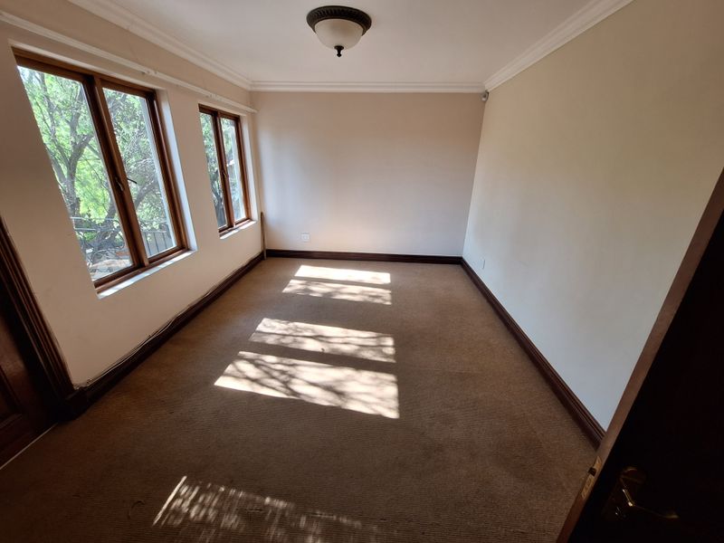 An empty bedroom featuring carpet flooring, timber window frames, and neutral wall finishes, offering a blank canvas for personalization.