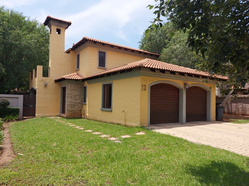 Front exterior view of a two-story house featuring a double garage, terracotta roof tiles, and a textured stucco finish with stone accents.