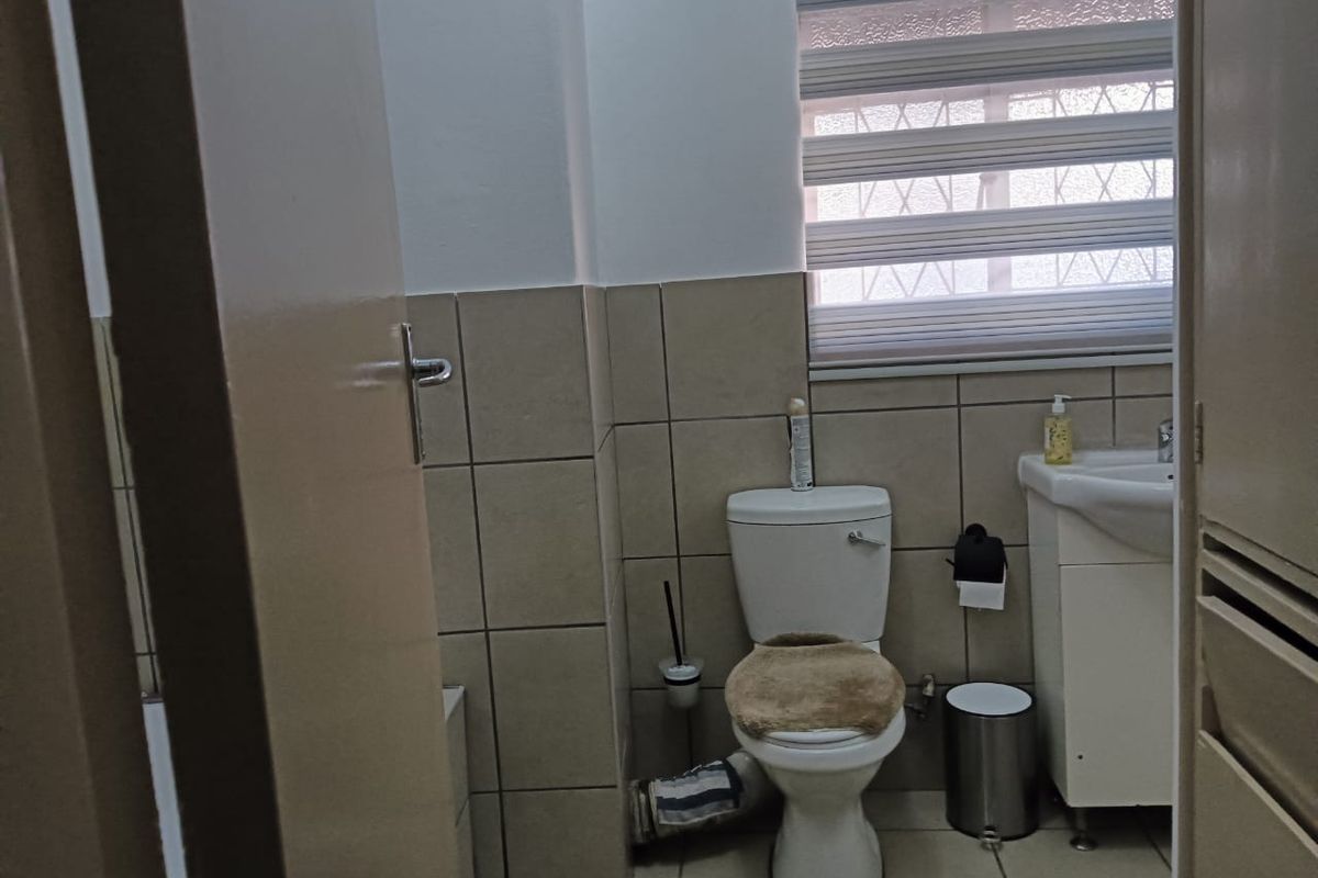 A functional bathroom featuring a standard toilet, pedestal basin, and tiled walls, providing a practical layout for daily use.