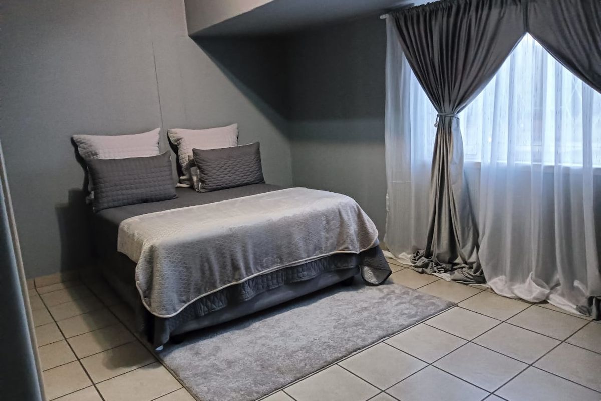 A bedroom featuring tiled flooring and neutral grey wall finishes, providing a clean and functional living space.