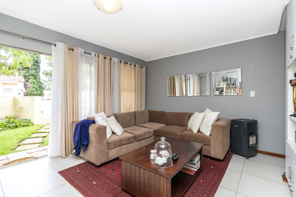 A living room featuring tiled flooring and a large sliding glass door providing direct access to the garden area.
