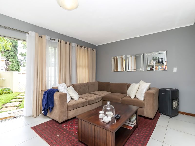 A living room featuring tiled flooring and a large sliding glass door providing direct access to the garden area.