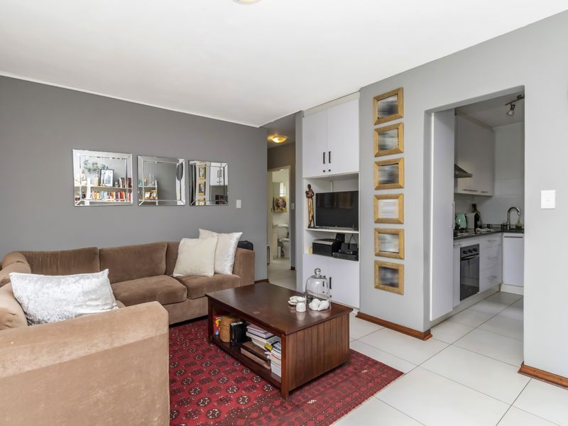 Open plan living area featuring tiled floors and built-in cabinetry, with a direct view into the adjacent kitchen space.