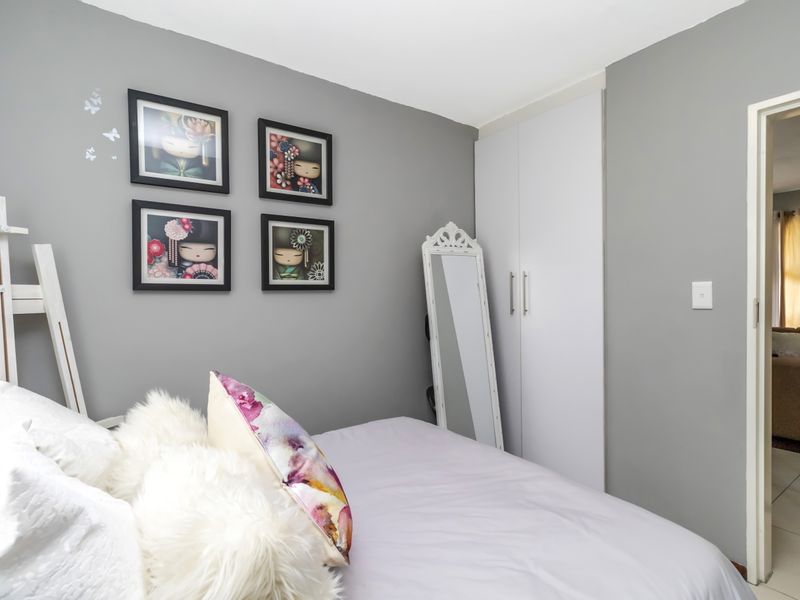 A well-maintained bedroom featuring neutral grey walls and a functional built-in wardrobe with white doors.