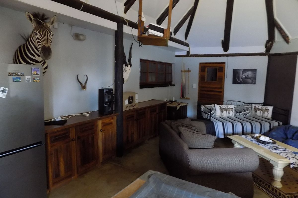 A rustic living area featuring exposed timber ceiling beams, built-in wooden cabinetry, and concrete flooring in a circular room layout.