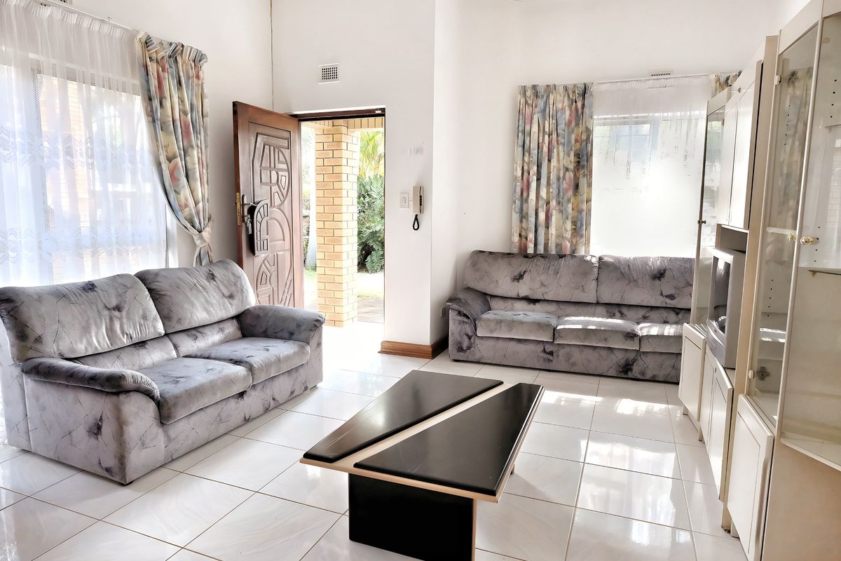 A bright living room featuring large windows, tiled flooring, and direct access to an outdoor patio area.