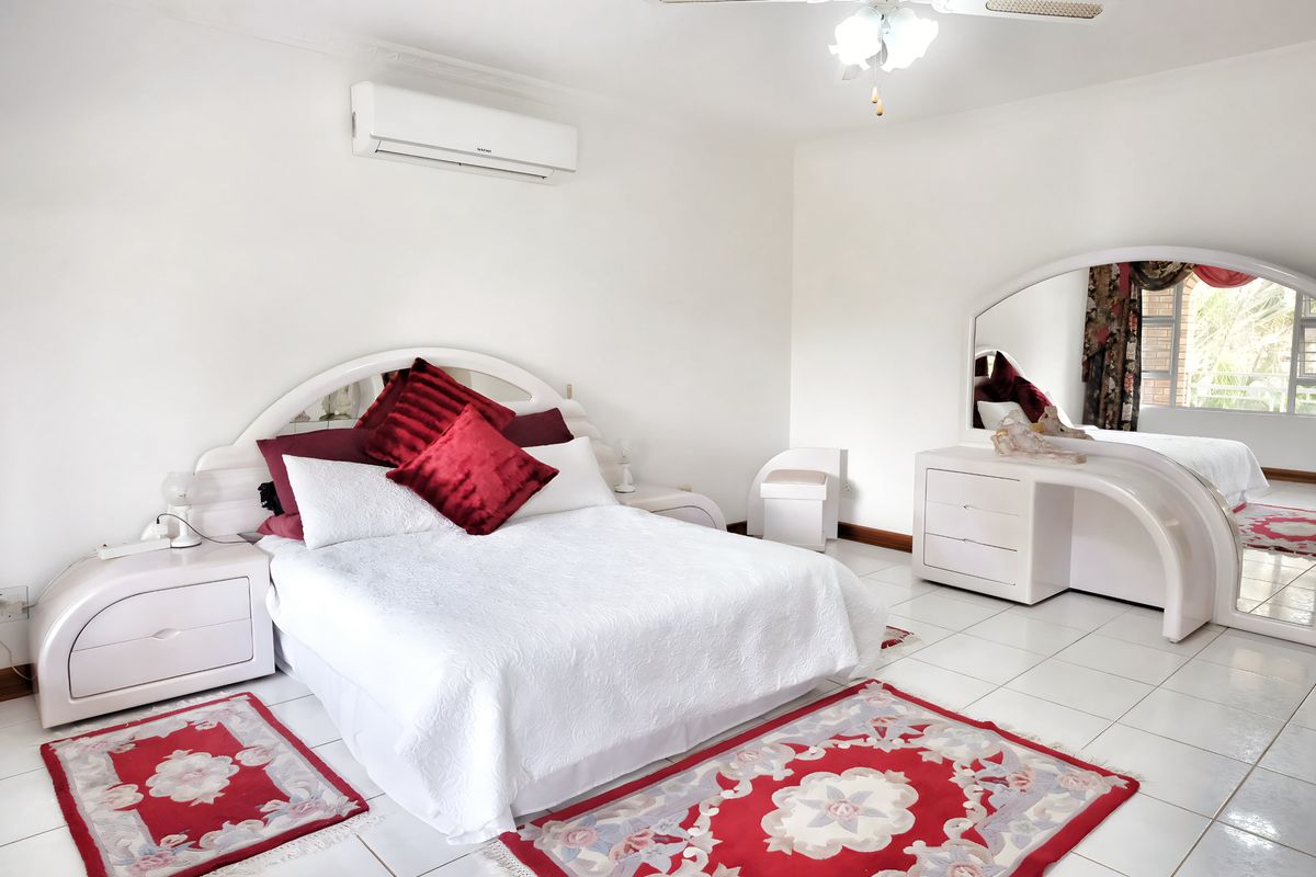 Spacious bedroom featuring white tiled flooring, a wall-mounted air conditioning unit, and a ceiling fan.
