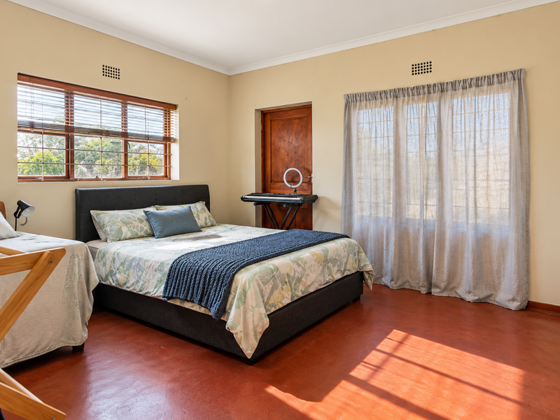 Spacious bedroom featuring warm terracotta flooring, built-in cupboards, and dual windows allowing for ample natural light.
