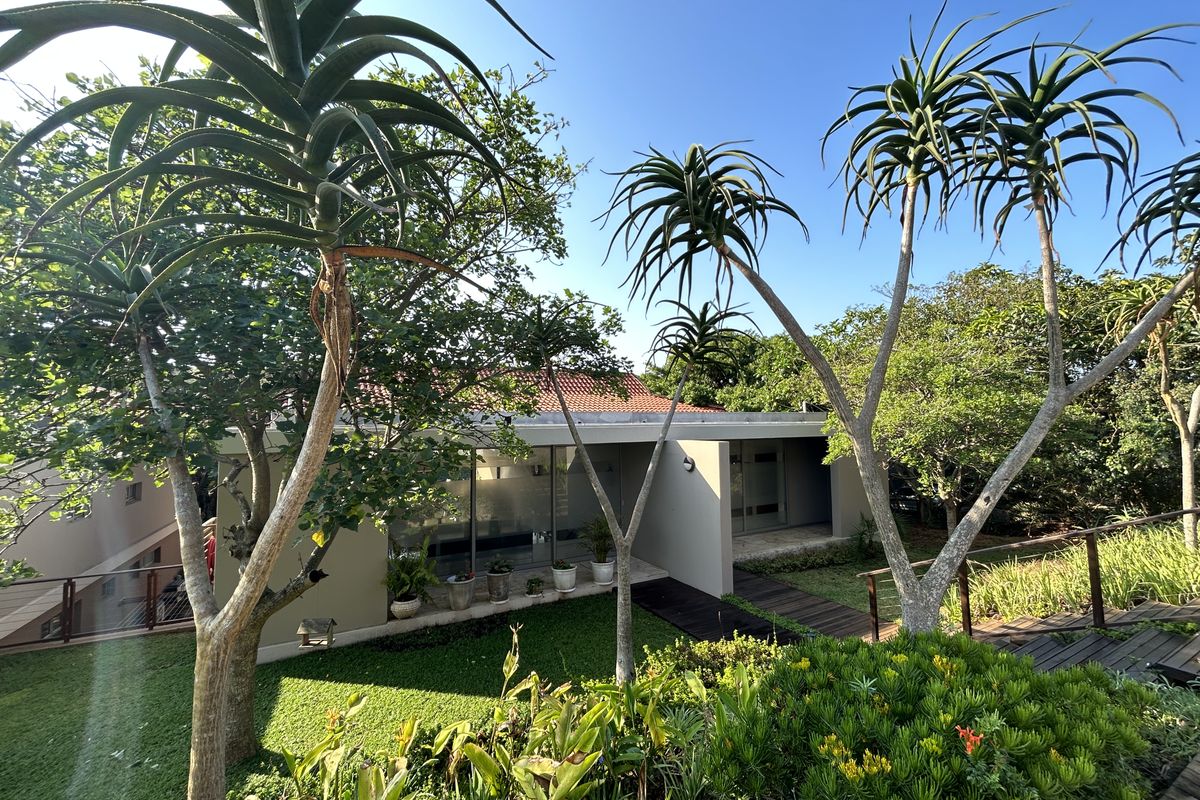 A well-maintained rear exterior view of the townhouse featuring a landscaped garden, timber decking, and large sliding glass doors leading to the interior.