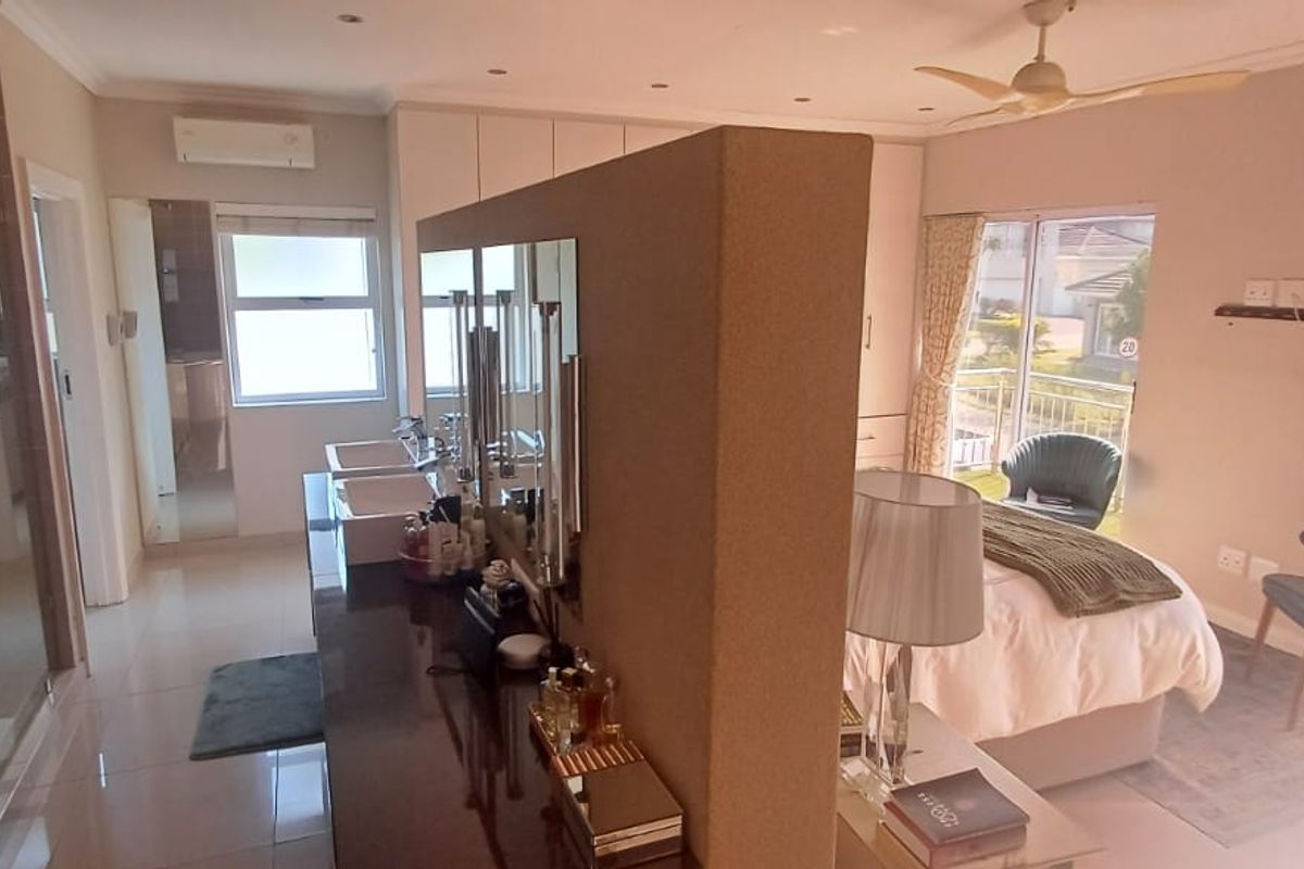 Spacious bedroom featuring an open-plan en-suite bathroom with a double vanity, glass shower, built-in cupboards, and direct access to a private balcony.