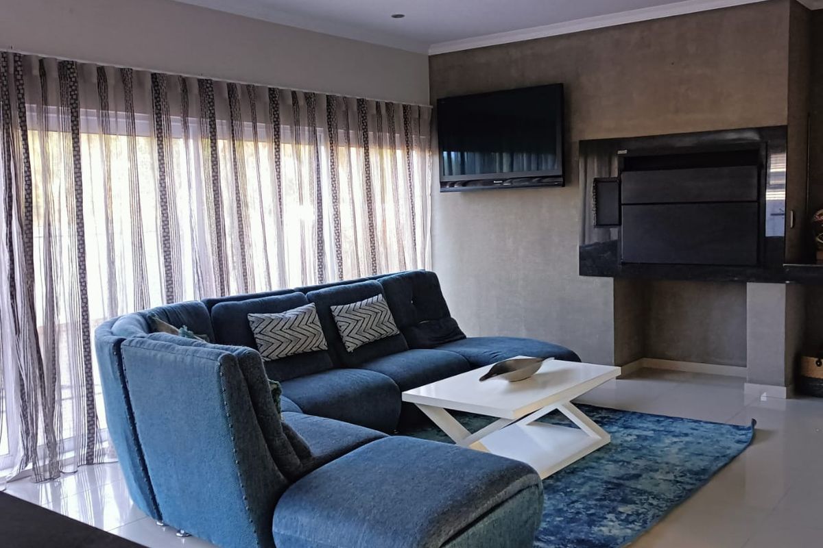Modern living room featuring a built-in fireplace, recessed ceiling lighting, tiled floors, and large sliding glass doors providing ample natural light.