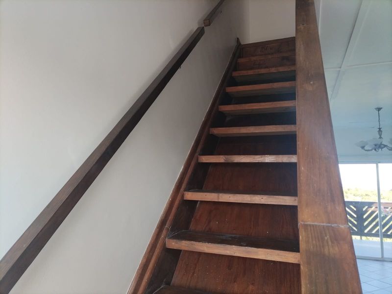 A functional wooden staircase with a matching handrail, providing access between levels in the flat.