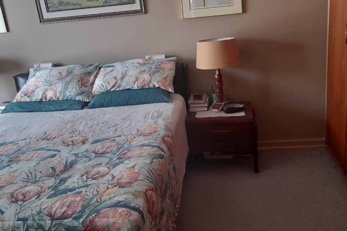 A bedroom featuring built-in wooden cupboards and carpeted flooring.
