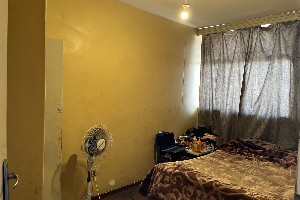 A bedroom featuring yellow painted walls, tiled flooring, and a window with curtain treatments.