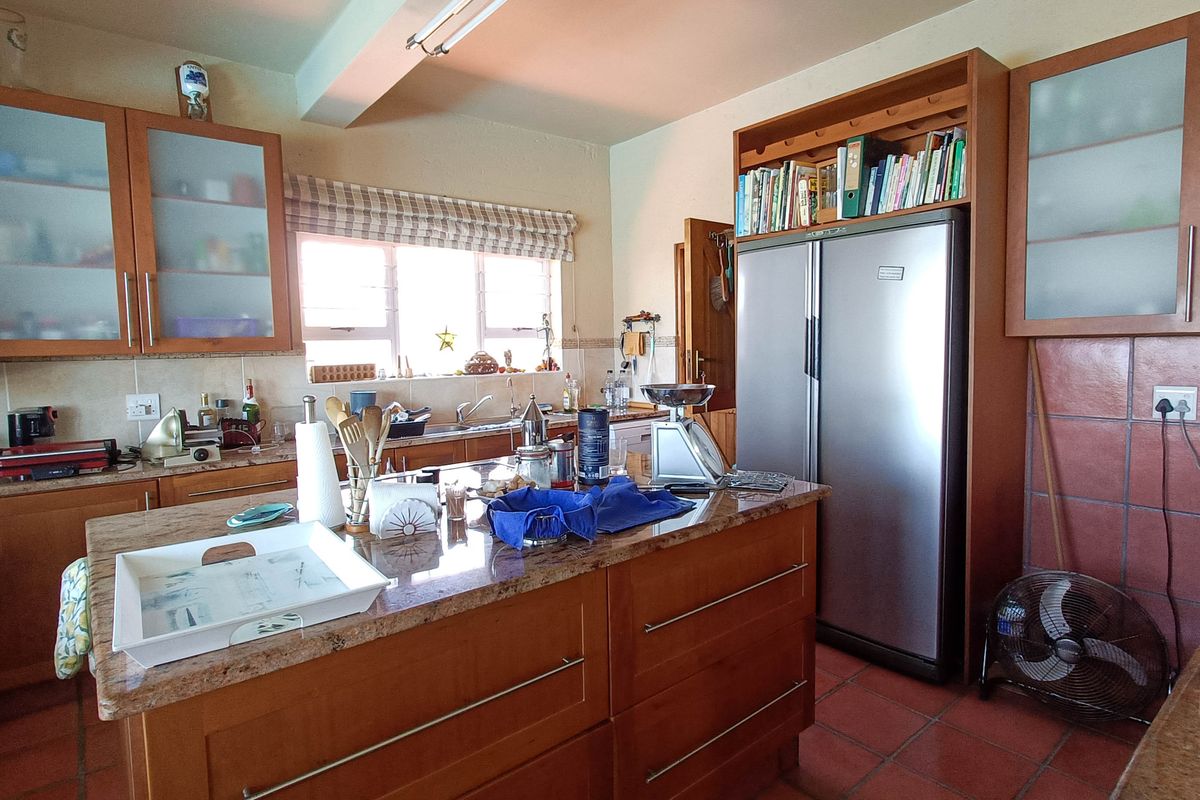 A functional kitchen featuring wooden cabinetry, granite countertops, a central island, and tiled flooring, offering a traditional layout with ample storage space.