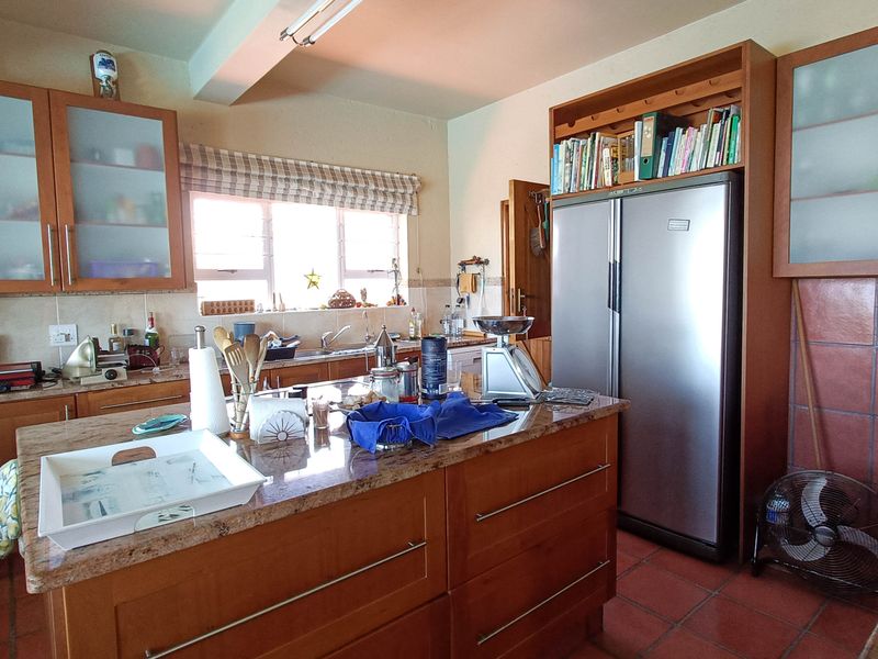 A functional kitchen featuring wooden cabinetry, granite countertops, a central island, and tiled flooring, offering a traditional layout with ample storage space.