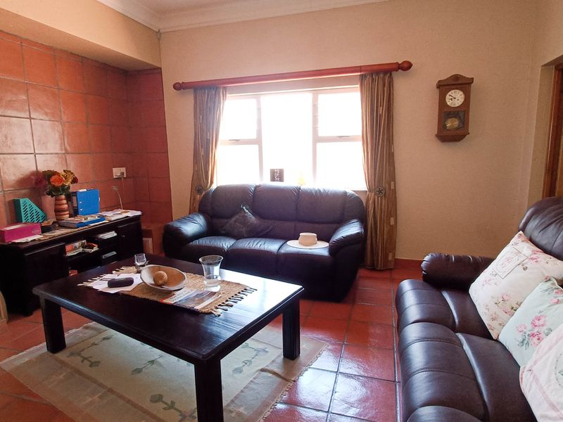 A living room featuring terracotta floor tiles and a matching tiled feature wall, providing a warm and traditional aesthetic.