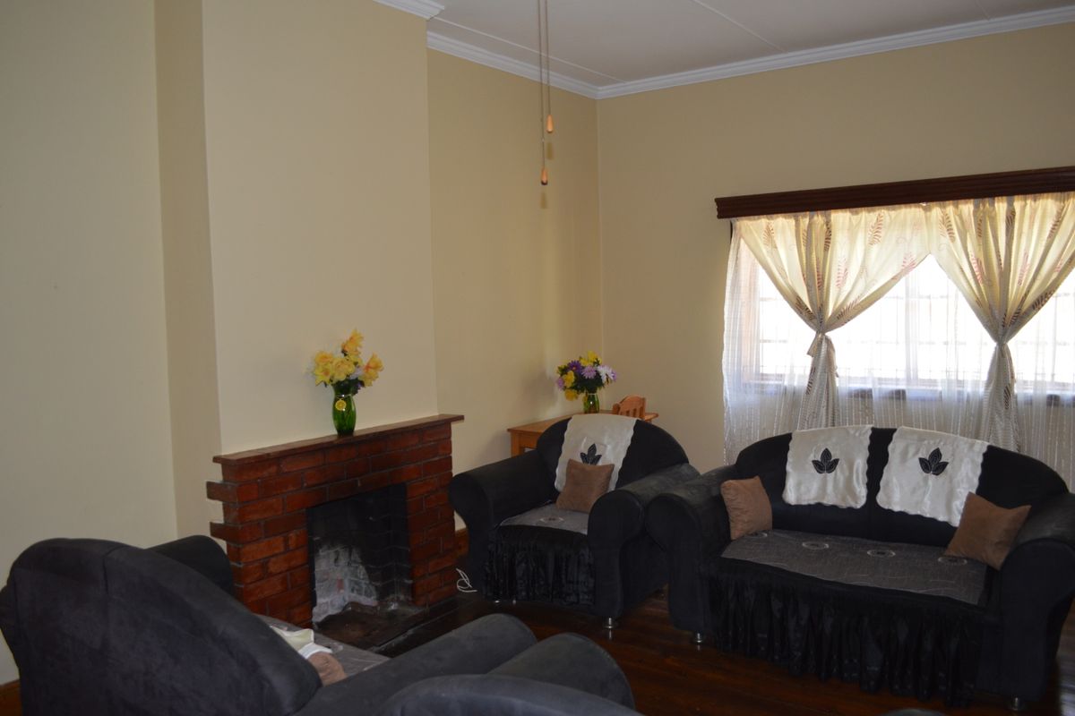 A cozy living room featuring a traditional brick fireplace, hardwood flooring, and crown molding, providing a warm and inviting atmosphere.
