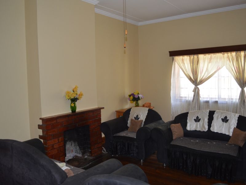 A cozy living room featuring a traditional brick fireplace, hardwood flooring, and crown molding, providing a warm and inviting atmosphere.