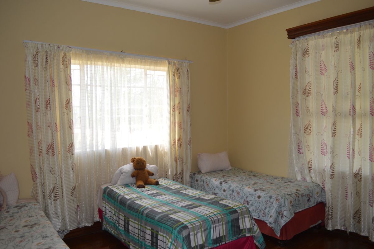 A bedroom featuring timber flooring and dual windows with installed curtain rails, providing natural light to the space.