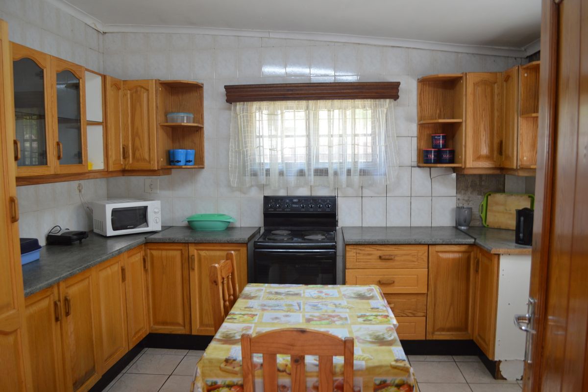 A dated kitchen featuring wooden cabinetry, tiled backsplash, and a freestanding electric stove, offering a functional layout with potential for modern updates.