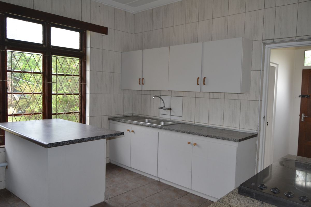 A functional kitchen featuring white cabinetry, granite-look countertops, a double sink, and tiled walls, offering a clean and practical workspace.