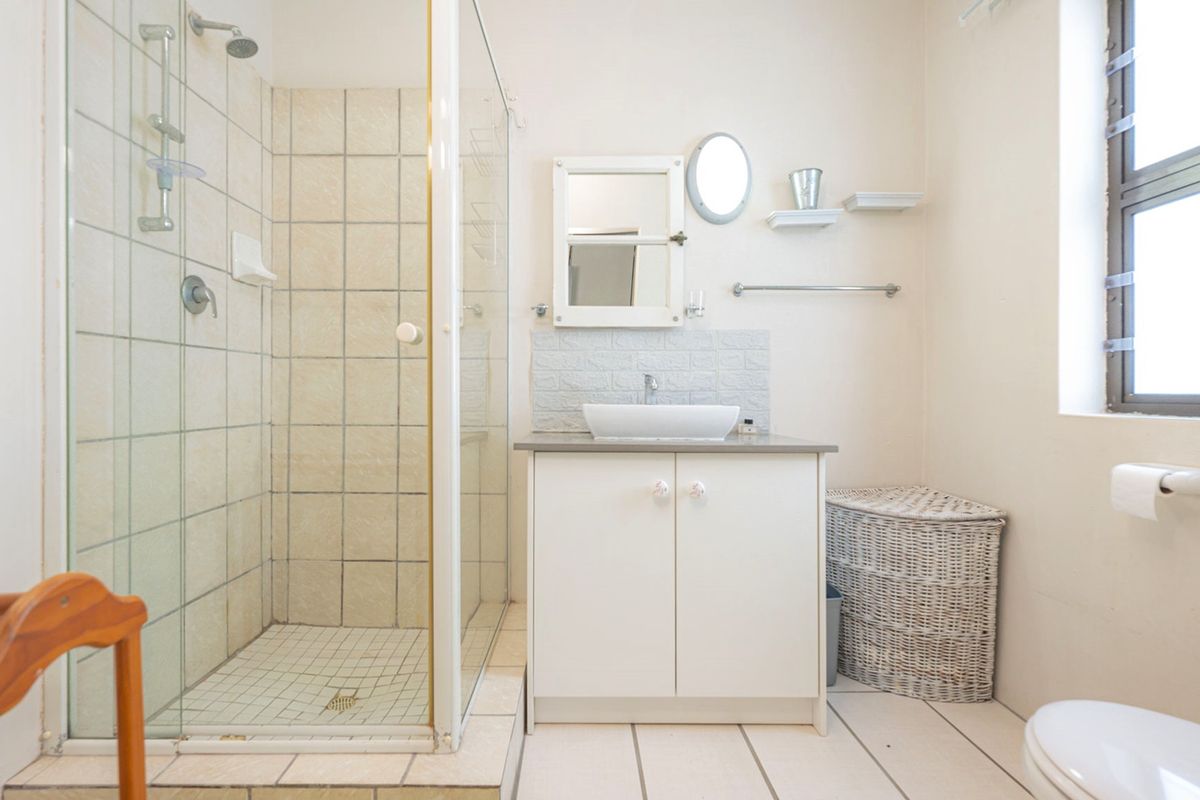A functional bathroom featuring a glass-enclosed shower, a modern vessel sink vanity, and a standard toilet with tiled flooring.