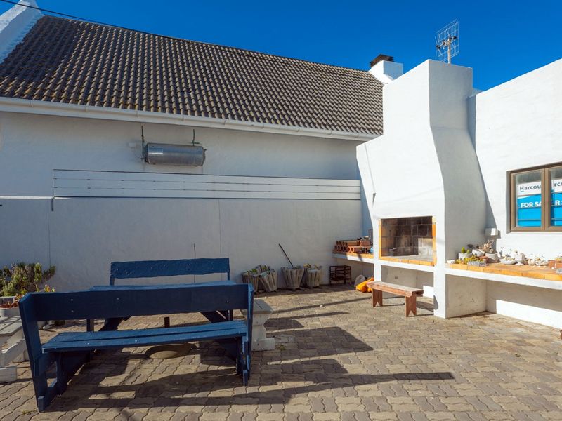 Outdoor patio area featuring a built-in braai, paved flooring, and a boundary wall, providing a functional space for outdoor entertaining.