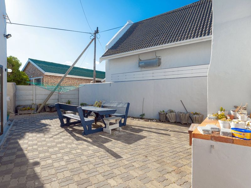A paved outdoor patio area featuring a built-in braai and enclosed by boundary walls, providing a functional space for outdoor entertaining.