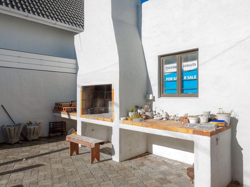 Outdoor patio area featuring a built-in masonry braai and preparation counter, finished with paved flooring and a solid timber door.