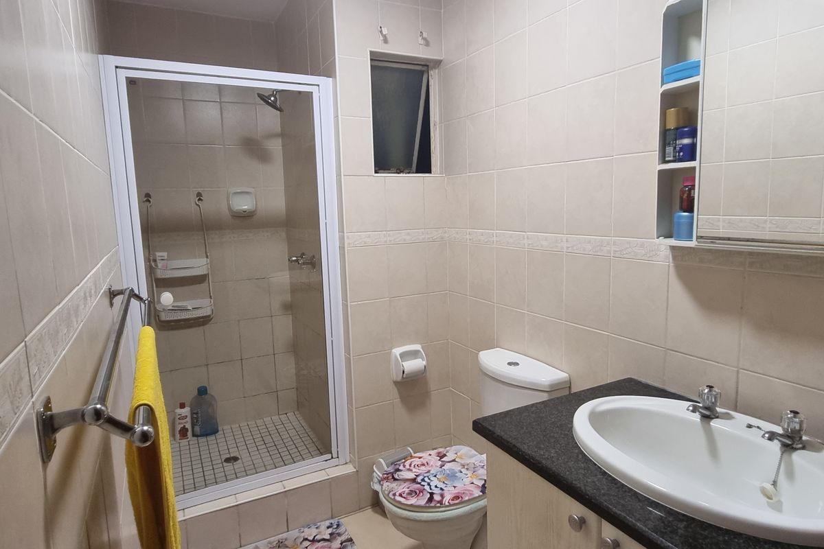 A functional bathroom featuring a shower enclosure, vanity with basin, and tiled finishes throughout.