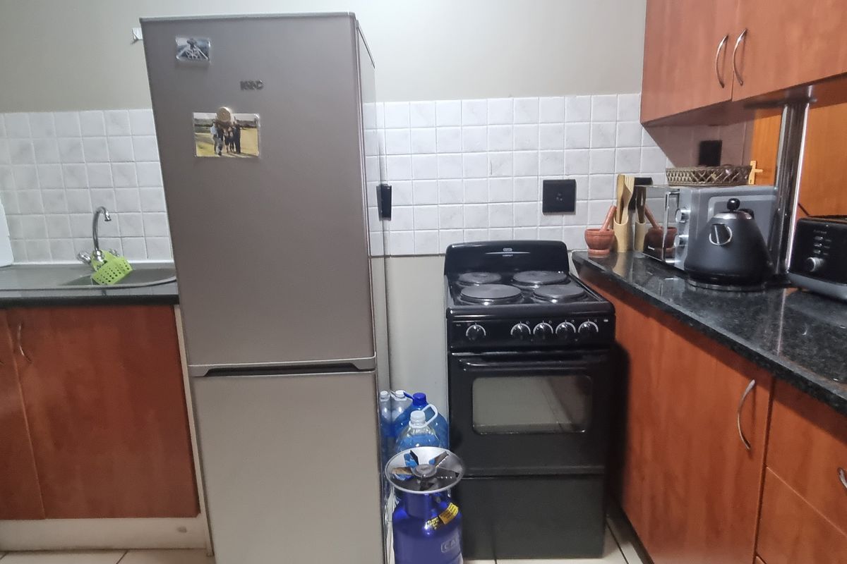 A functional kitchen featuring laminate cabinetry, granite countertops, a tiled backsplash, and a freestanding electric stove.