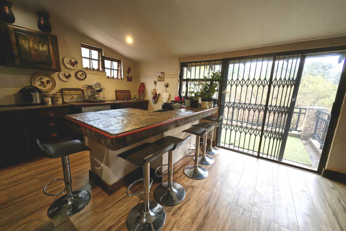 A kitchen featuring a stone-topped breakfast bar, tiled splashback, and direct access to an outdoor area through a sliding security door.