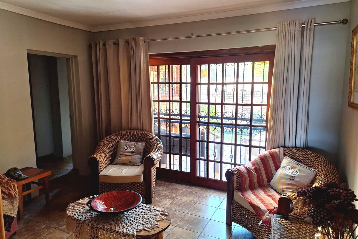 A living room featuring tiled flooring and sliding glass doors with security gates, providing access to the outdoor area.