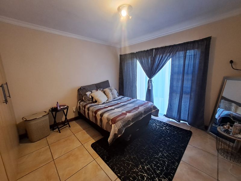 A bedroom featuring tiled flooring, built-in cupboards, and a sliding glass door providing access to the exterior.