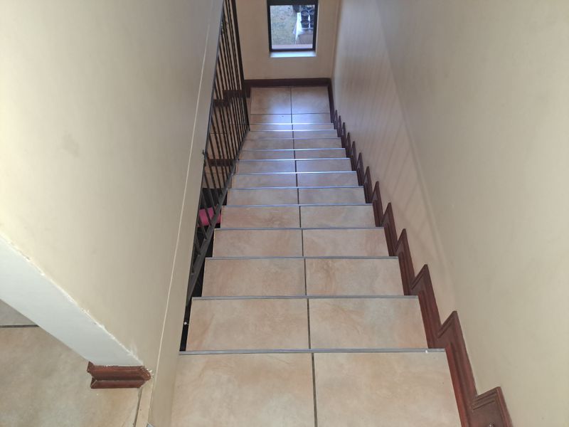 A tiled staircase featuring a metal balustrade and neutral wall finishes, providing access between levels in the apartment.
