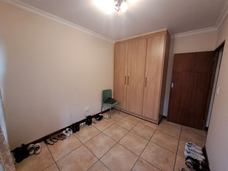 A bedroom featuring tiled flooring, coving, and a built-in wooden wardrobe, offering a functional space ready for personalization.