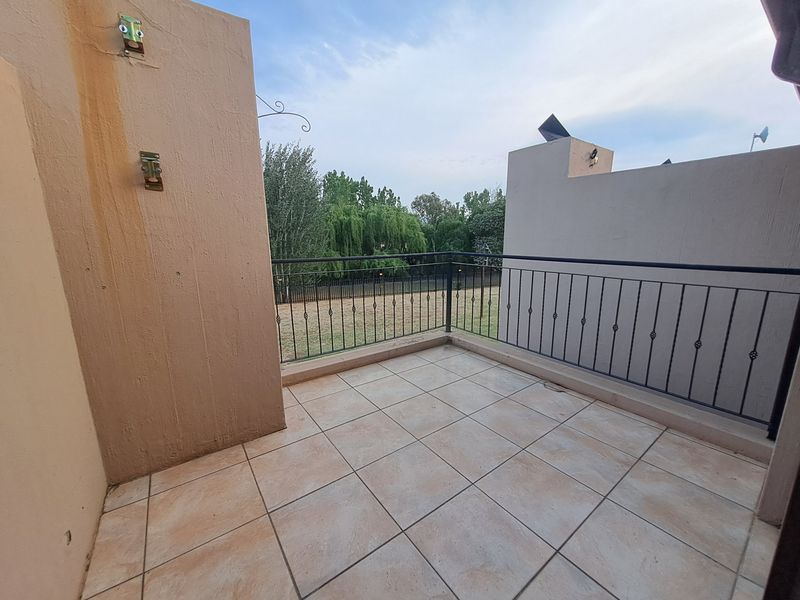 A private balcony featuring tiled flooring and a metal balustrade, offering an open view of the surrounding greenery.