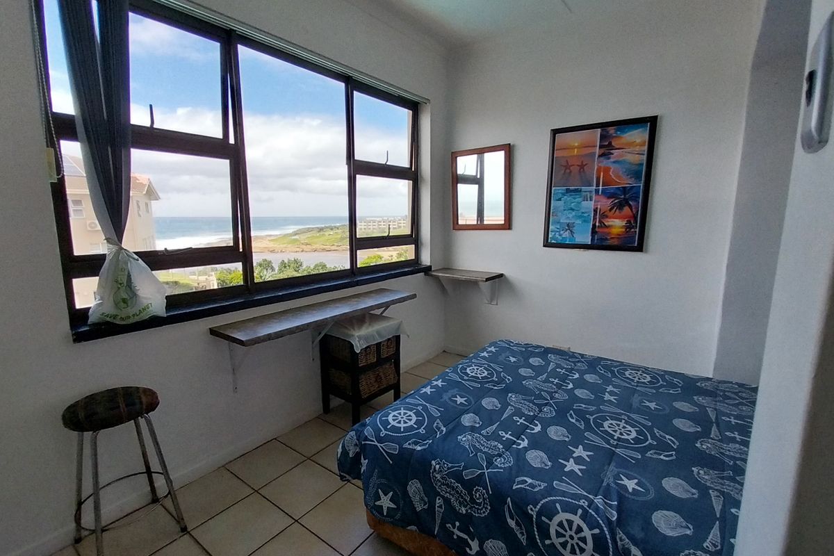 A bedroom featuring large windows with ocean views, tiled flooring, and built-in shelving units.