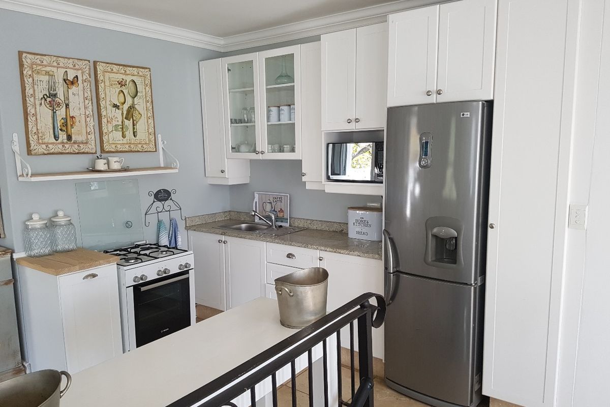 A well-maintained kitchen featuring white cabinetry, granite countertops, a gas stove, and built-in microwave, offering a clean and functional cooking space.