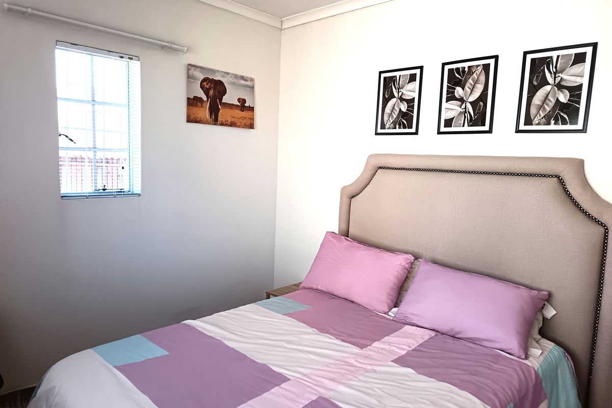 A functional bedroom featuring a window with security bars and neutral wall finishes.